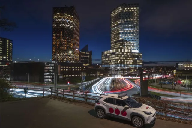 Securitas-Fahrzeug steht bei Nacht vor beleuchteten Hochhäusern und Straßenverkehr mit Lichtspuren